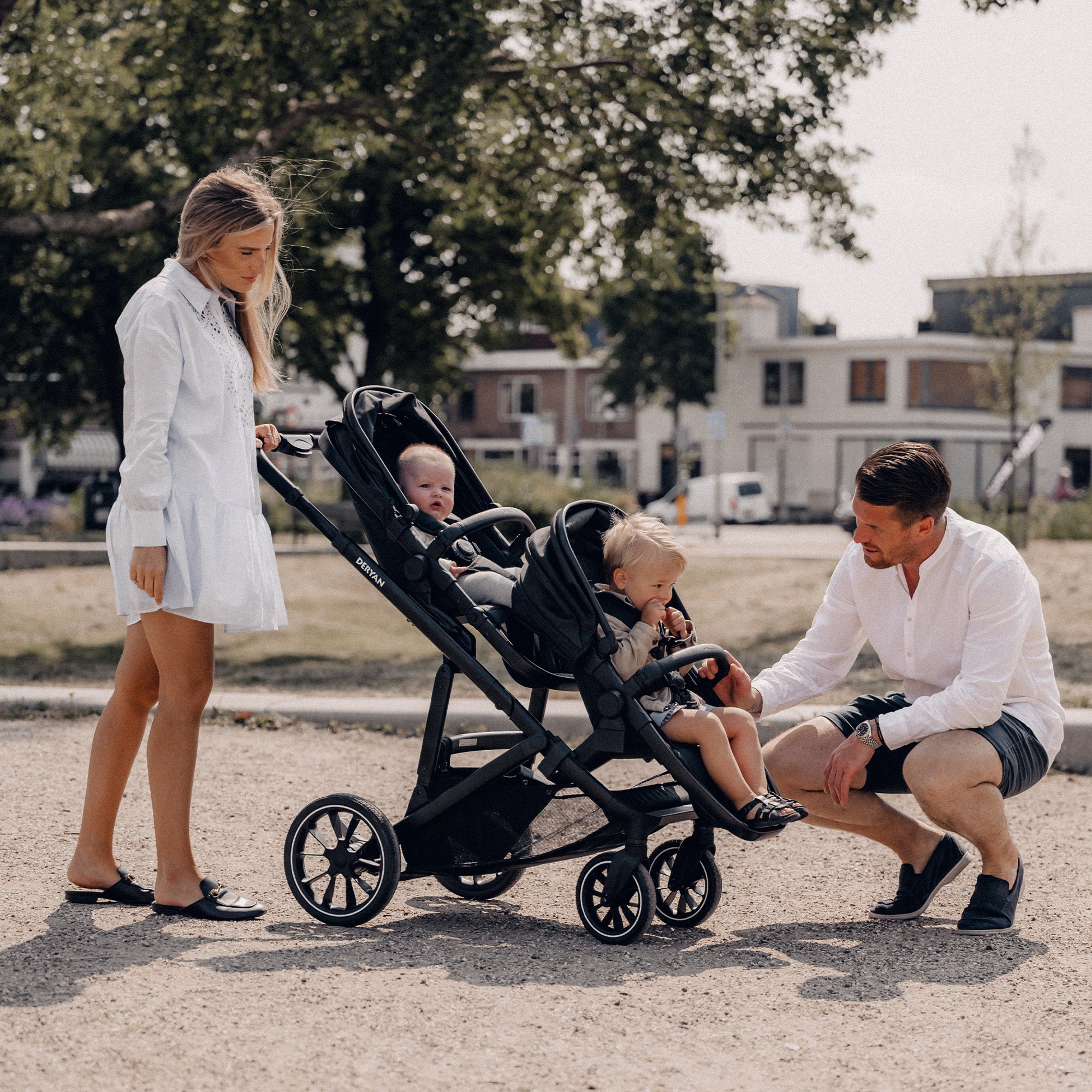 De DERYAN EVY V2 Duo Kinderwagen in het zwart heeft twee zitplaatsen en een ontwerp dat met één hand kan worden ingeklapt. Het model heeft verstelbare zitjes en een voetensteun, een zonnekap met SPF vijftig plus, een veringssysteem en een vijfpuntsgordel voor beide zitposities.