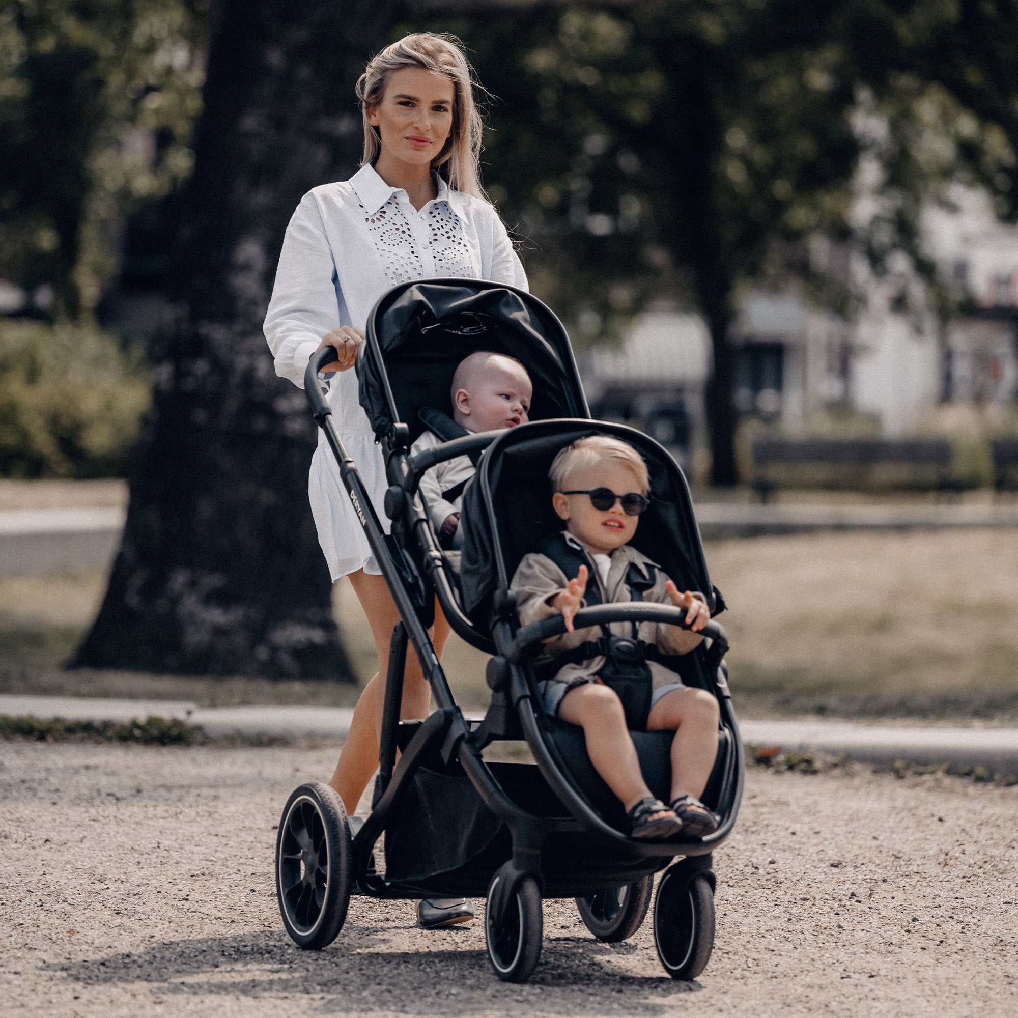 De DERYAN EVY V2 Duo Kinderwagen in het zwart heeft twee zitplaatsen en een ontwerp dat met één hand kan worden ingeklapt. Het model heeft verstelbare zitjes en een voetensteun, een zonnekap met SPF vijftig plus, een veringssysteem en een vijfpuntsgordel voor beide zitposities.